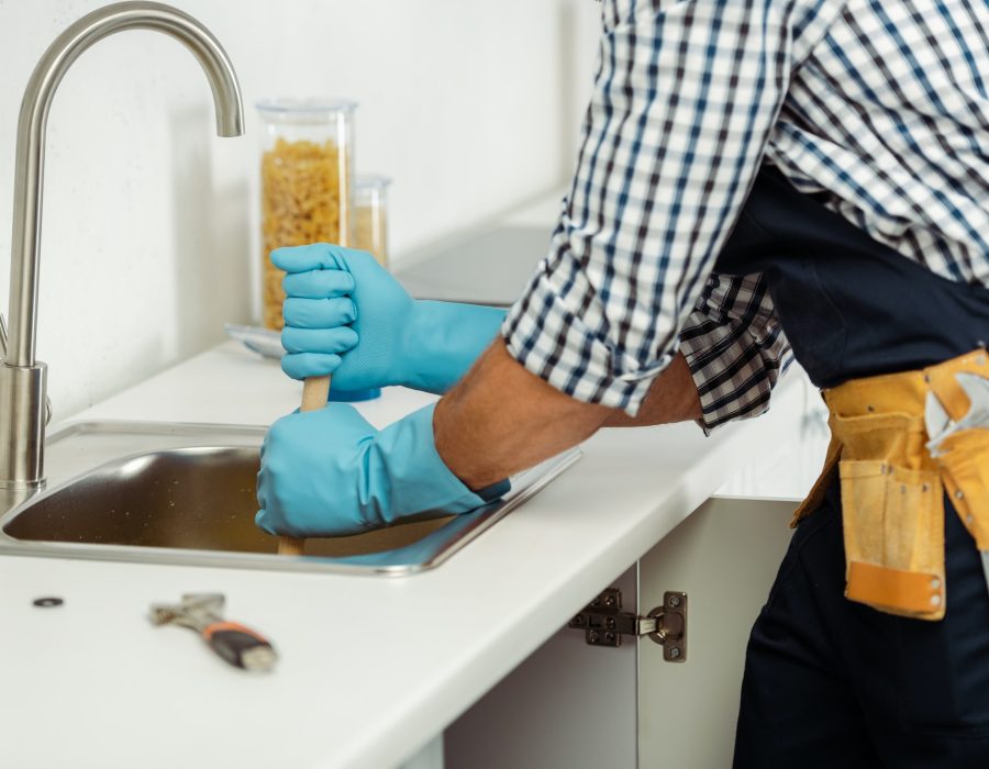 cropped-view-of-plumber-in-tool-belt-and-rubber-gloves-cleaning-blockage-of-kitchen-sink.jpg
